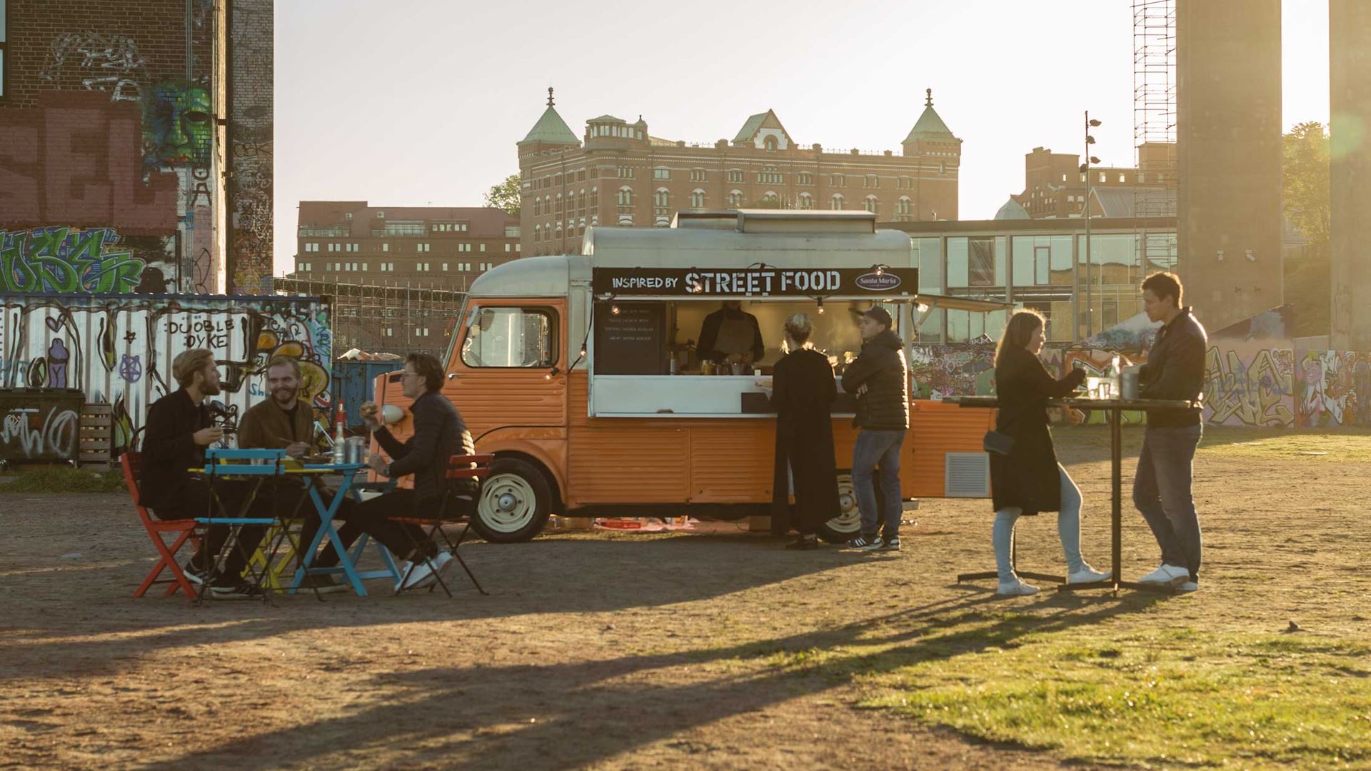 Folk spiser foran en food truck.