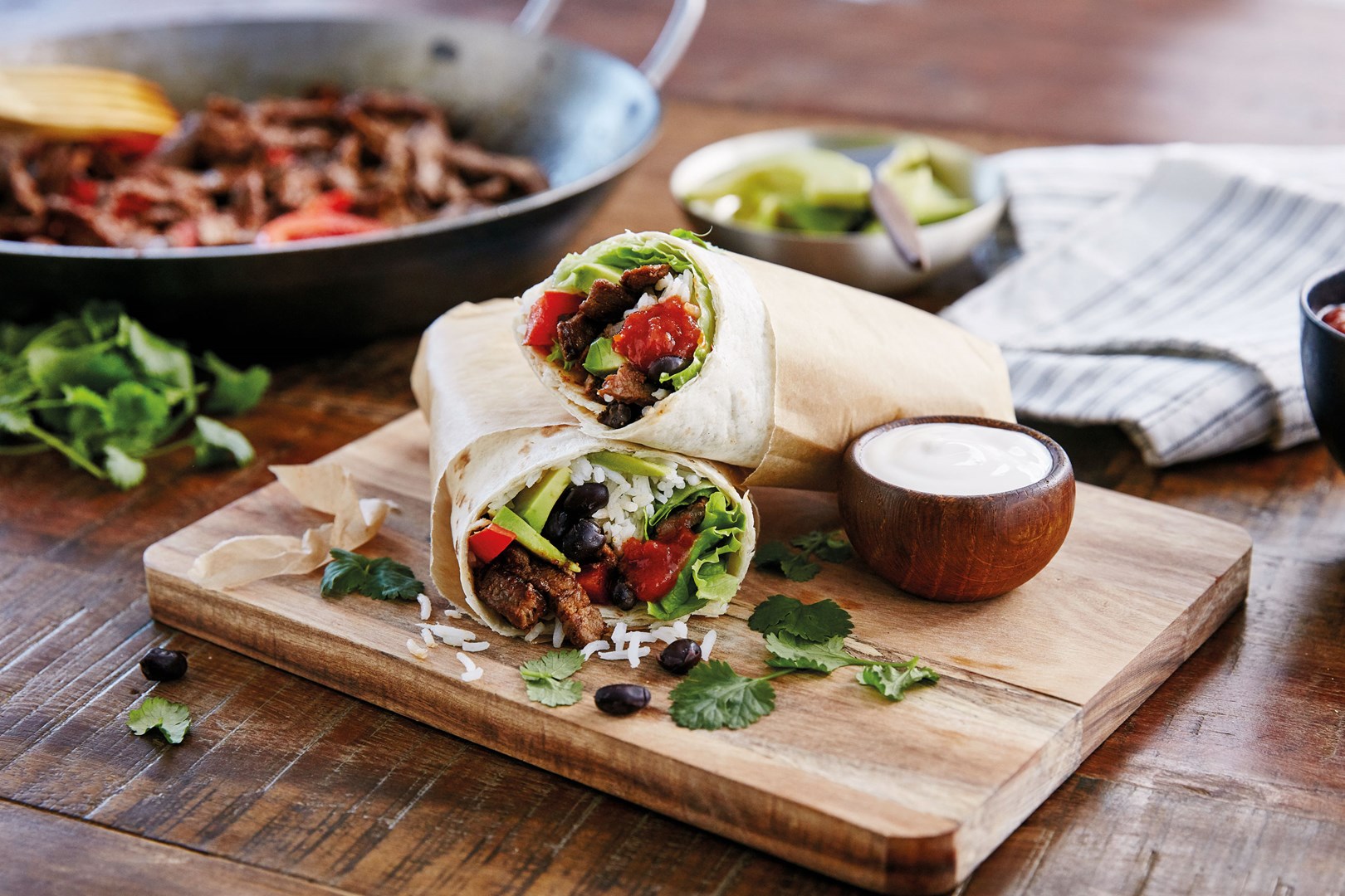 2 halve beef burrito's gevuld met rundvlees, rijst en groenten op een plankje