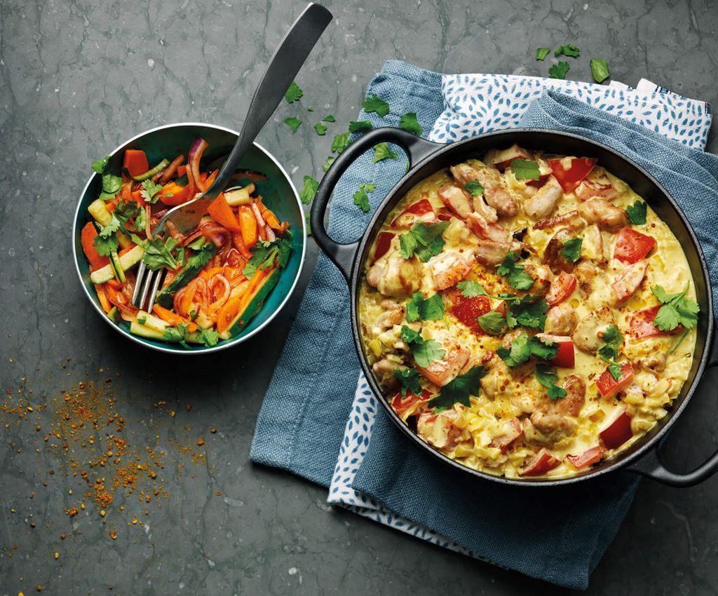 Currykyckling i en gryta med sallad i en skål bredvid