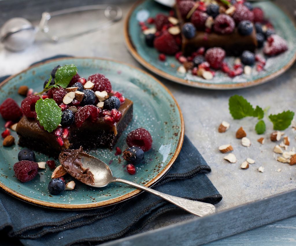 Vegansk brownie med färska bär och mandlar på en tallrik