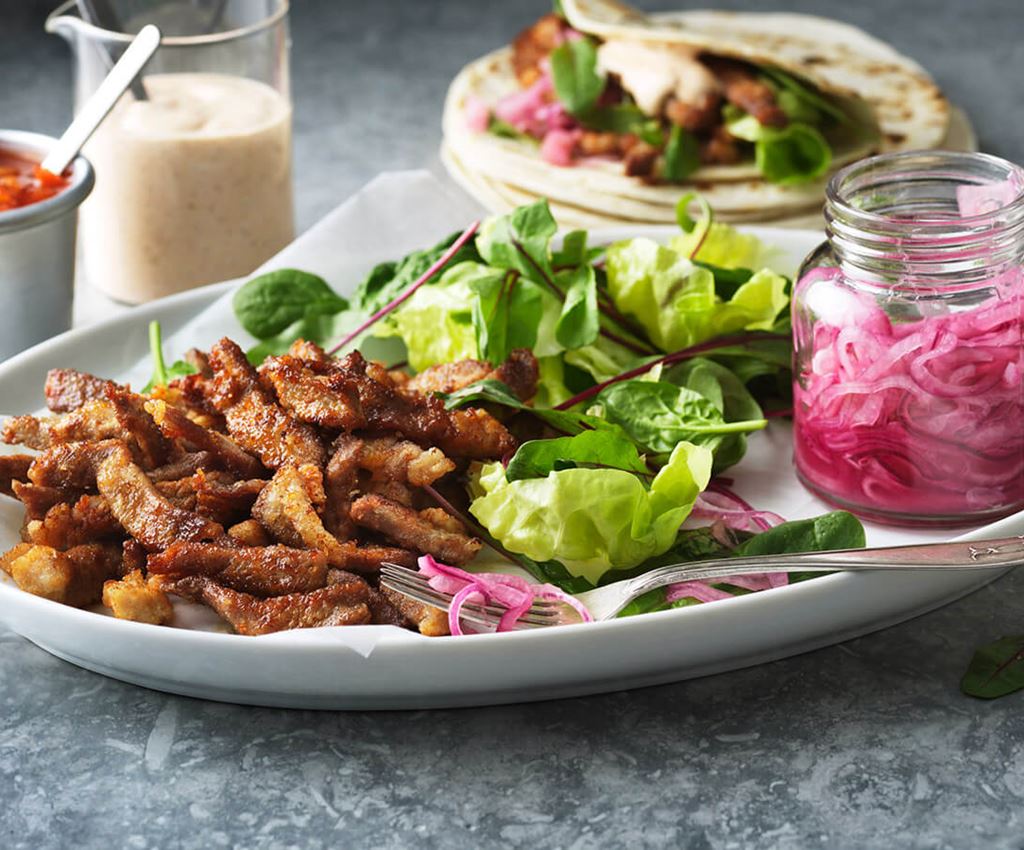 Chicharrónes på en tallrik med en burk picklad rödlök