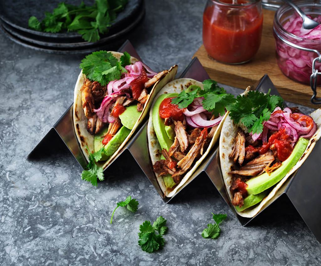 Three pulled pork tacos on a tray