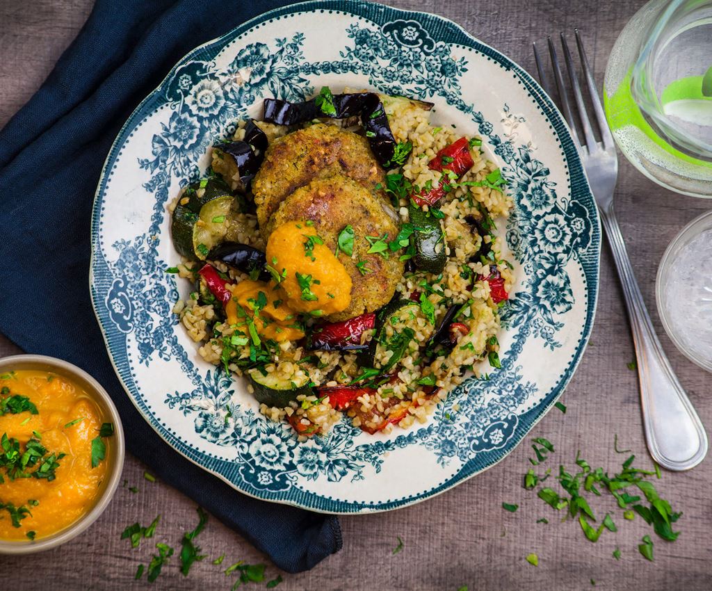 Kikärstbiffar med bulgur och rostade grönsaker på en tallrik