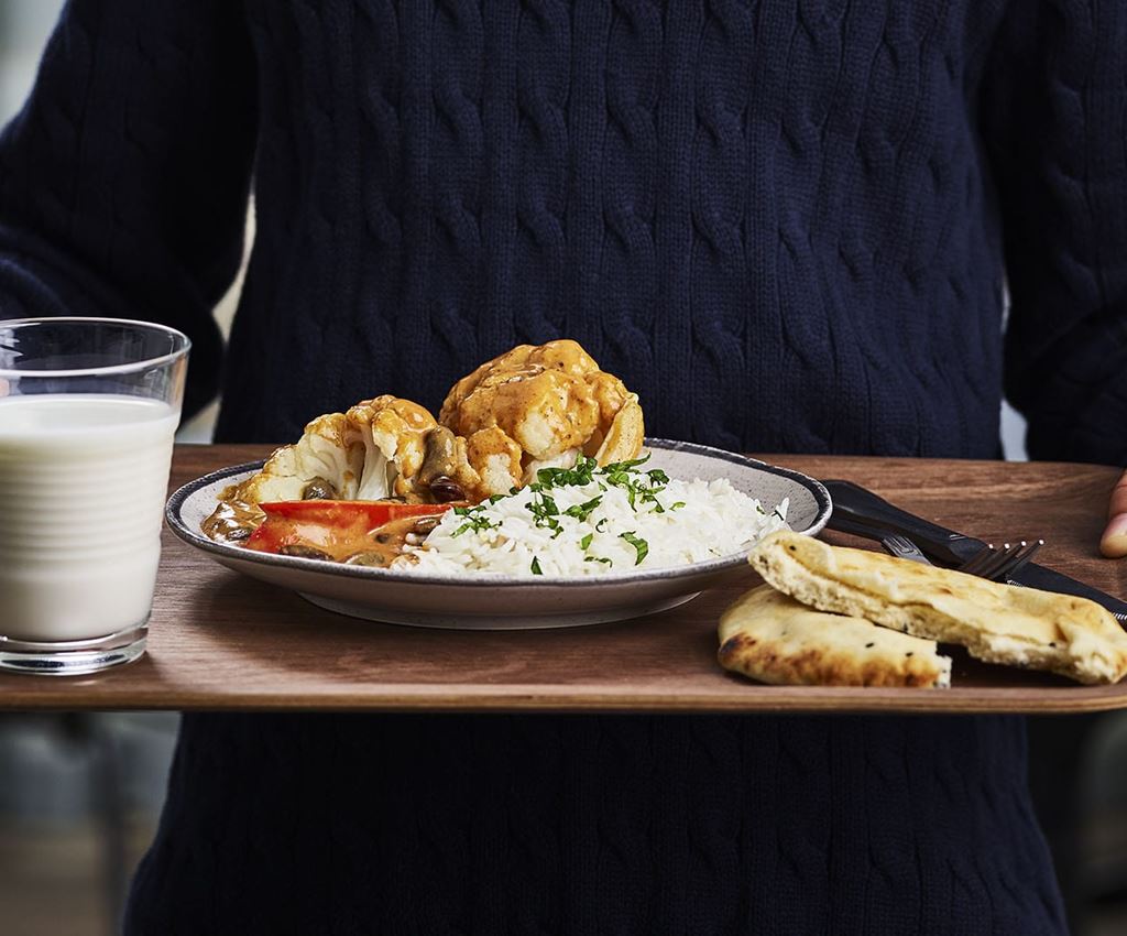 Person håller en bricka med vegetarisk tikka