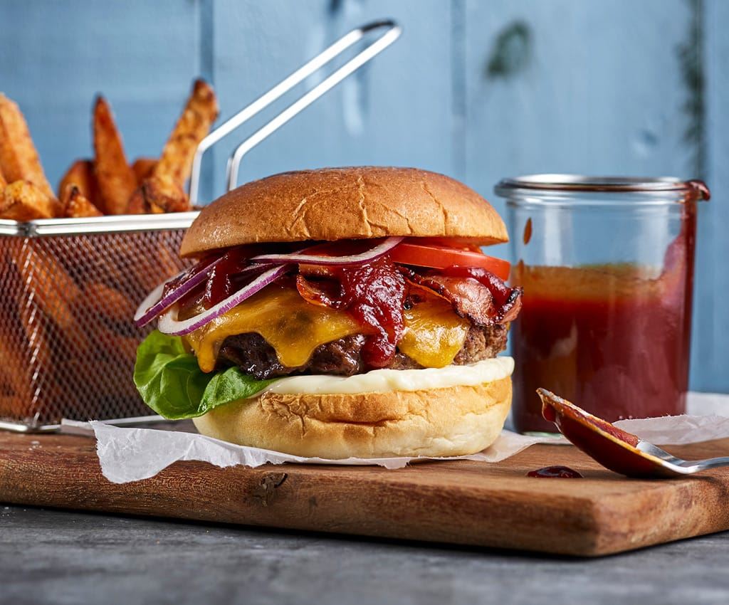 Cheese burger med pommes frites og saus på en på en fjøl